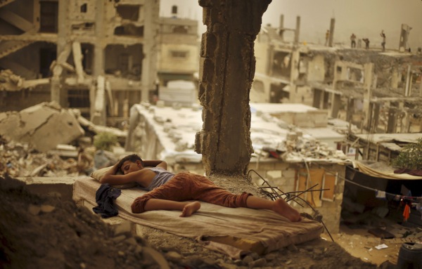 A Palestinian boy sleeps on a mattress inside the remains of his family's house, that witnesses said was destroyed by Israeli shelling during a 50-day war in 2014 summer, during a sandstorm in Gaza September 8, 2015. A heavy sandstorm swept across parts of the Middle East on Tuesday, killing two people and hospitalising hundreds in Lebanon and disrupting fighting and air strikes in neighbouring Syria. Clouds of dust also engulfed Israel, Jordan and Cyprus where aircraft were diverted to Paphos from Larnaca airport as visibility fell to 500 metres. REUTERS/Suhaib Salem TPX IMAGES OF THE DAY - RTX1RMX8